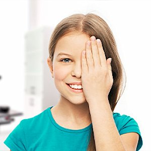 Child holding hand over one eye during eye exam